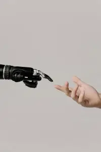 A human hand reaching to touch a bionic prosthetic hand on a white background.